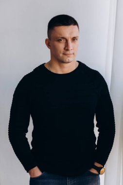 Stüdyoda poz veren sıradan kıyafetler giymiş genç yakışıklı bir adam. 