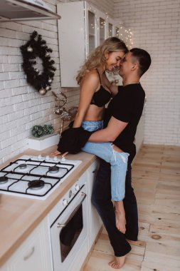 Güzel bir çift, arka planda Noel süsleriyle mutfakta şehvetle poz veriyor.