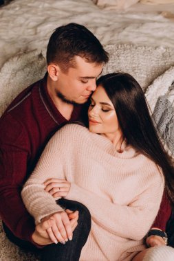 Stüdyoda rahat bir Noel süslemesiyle yatakta poz veren birbirine aşık genç bir çift. Yeni yılın aşk hikayesi.. 