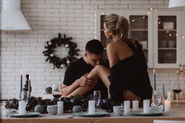 Kadın mutfak masasında otururken, erkek bacaklarını öperken, Noel süslemeleri yaparken.