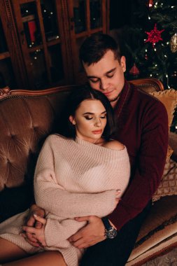 Stüdyoda rahat bir Noel süslemesi ile kanepede poz veren birbirine aşık genç bir çift. Yeni yılın aşk hikayesi.. 