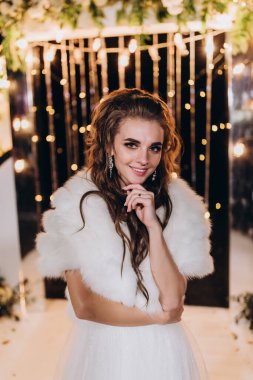 Genç ve güzel bir gelin, özel gününde göz kamaştırıcı düğün süslerinin önünde zarifçe poz verir..