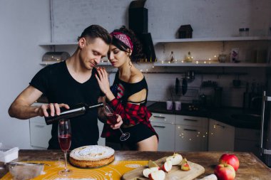 Genç ve tutkulu bir çift mutfakta şarap içiyor. 