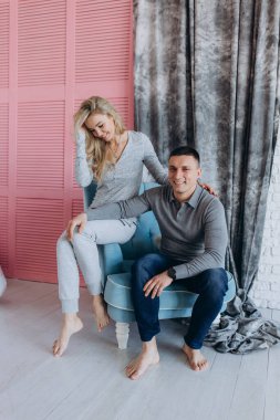 Güzel, genç bir çift, günlük giysiler içinde, birlikte poz veriyorlar ve rahat bir odada gülüyorlar.    