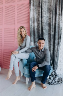 Güzel, genç bir çift, günlük giysiler içinde, birlikte poz veriyorlar ve rahat bir odada gülüyorlar.    