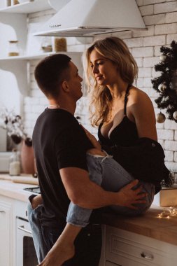 Güzel bir çift, arka planda Noel süsleriyle mutfakta şehvetle poz veriyor.