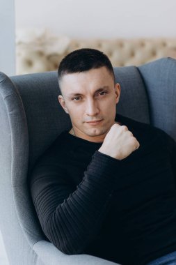 Stüdyoda poz veren sıradan kıyafetler giymiş genç yakışıklı bir adam. 