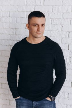 Stüdyoda poz veren sıradan kıyafetler giymiş genç yakışıklı bir adam. 