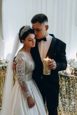 Genç gelin ve damat düğün töreninde mum tutuyorlar.