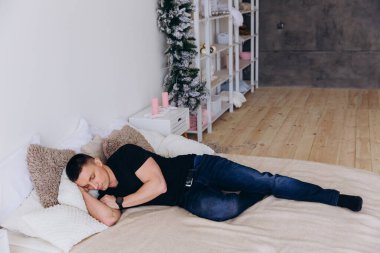 Genç bir adam huzur içinde bir yatakta uyuyor, sakin ve sessiz bir ortamda dinleniyor..