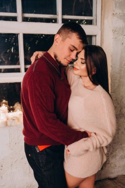 Birbirine aşık genç bir çift, süveter giyip öpüşüyor, stüdyoda poz veriyor ve samimi bir Noel süslemesi yapıyor. Yeni yılın aşk hikayesi.. 