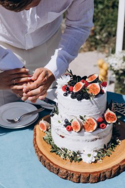 Gelin ve damat düğün masasında pasta kesiyorlar.