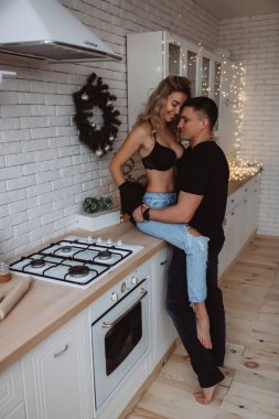 Güzel bir çift, arka planda Noel süsleriyle mutfakta şehvetle poz veriyor.