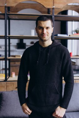 Genç bir adam modern bir odadaki şık bir kanepede günümüzün tarzıyla rahatlığı birleştiriyor..