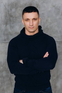 Genç adam stüdyoda poz veren siyah kapüşonlu günlük kıyafetler giyiyor.. 