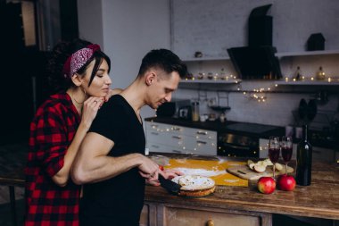 Genç ve tutkulu bir çift mutfakta birlikte yemek pişiriyor. 