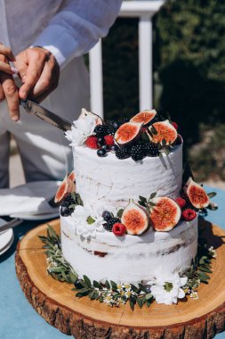Gelin ve damat düğün masasında pasta kesiyorlar.