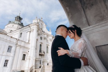 Eski kilisenin arka planında genç gelin ve damadın düşük açılı görüntüsü.    