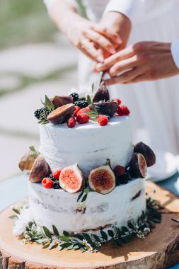 Gelin ve damat düğün masasında pasta kesiyorlar.