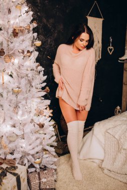 Stüdyoda rahat Noel süsleriyle poz veren genç bir kadın.. 