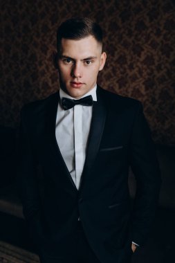 Şık takım elbiseli ve papyonlu yakışıklı genç adamın portresi.     