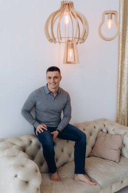 Stüdyoda poz veren sıradan kıyafetler giymiş genç yakışıklı bir adam. 