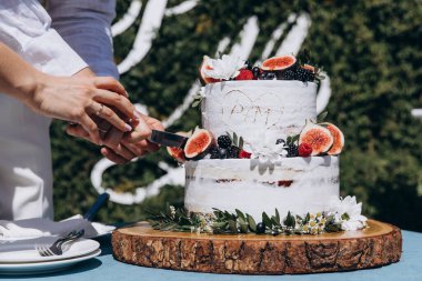 Gelin ve damat düğün masasında pasta kesiyorlar.