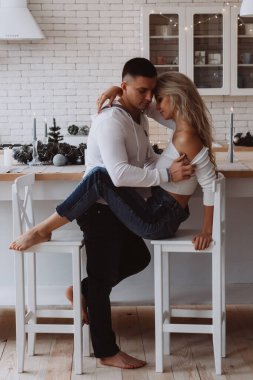 Uzun kollu beyaz elbiseli güzel bir çift mutfakta poz veriyor.