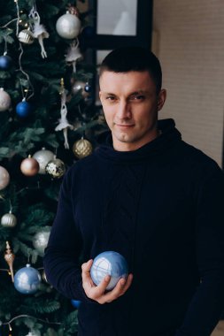 Stüdyoda Noel süsleriyle poz veren genç adam. 