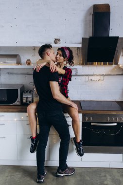 Genç ve tutkulu bir çift, sıcak bir mutfakta hassas bir anı paylaşıyor.
