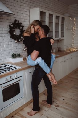 Güzel bir çift, arka planda Noel süsleriyle mutfakta şehvetle poz veriyor.