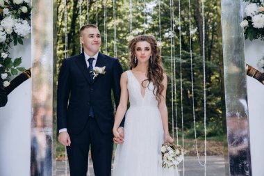 Genç bir düğün çifti, özel günlerinde güzel düğün süslemelerinin önünde romantik bir anın tadını çıkarır..