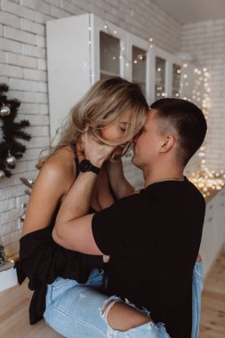 Güzel bir çift, arka planda Noel süsleriyle mutfakta şehvetle poz veriyor.