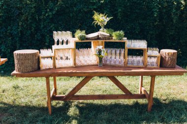 Bardaklar ve çiçeklerle açık havada düğün için şık bir masa.