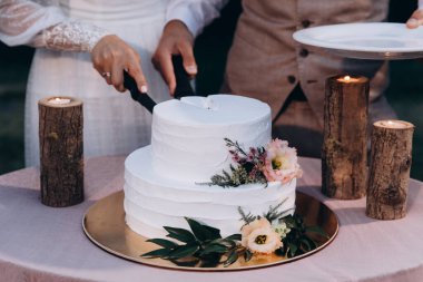 Gelin ve damat düğün pastasını çiçeklerle kesiyorlar..