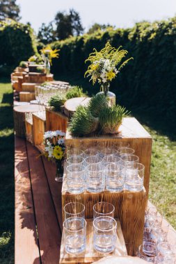 Bahçedeki güzel düğün dekorunun, çiçeklerin ve bardakların yakın çekimi.    