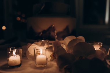 Gece vakti yanan mumların ve güzel çiçeklerin yakın görüntüsü.