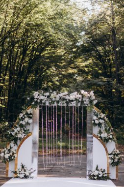 Parktaki açık hava töreni için çiçeklerle süslenmiş güzel bir düğün kemeri.     