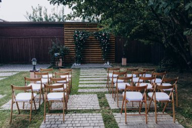 Güzel çiçek kemeri ve parktaki düğün töreninde sandalyeler.     