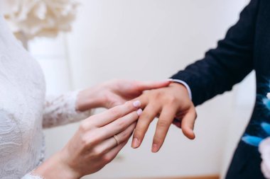 Tören sırasında yüzük takan genç çiftin yakın çekimi.