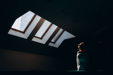 Beyaz cüppeli çekici bir kadın karanlık odada dikiliyor.    