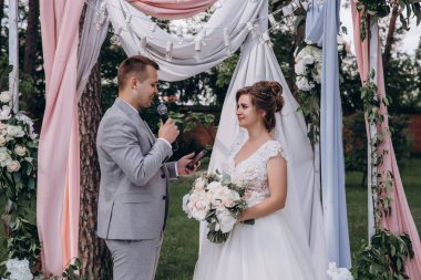 Güzel, mutlu, genç gelin ve damat açık havada evleniyor.