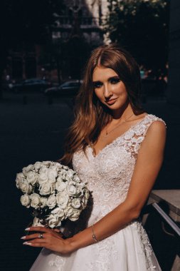 Beyaz gelinlikli güzel gelin şehirde poz veriyor.             