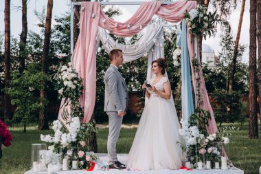 Güzel, mutlu, genç gelin ve damat açık havada evleniyor.