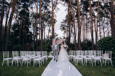 Güzel, mutlu, genç gelin ve damat açık havada evleniyor.