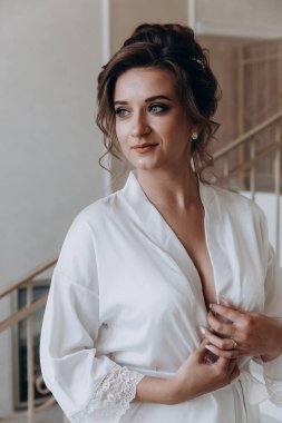 Beyaz bornozlu güzel gelinin portresi. Düğün sabahı evde.       