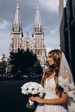 Beyaz gelinlikli güzel gelin şehirde poz veriyor.             