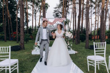 Güzel, mutlu, genç gelin ve damat açık havada evleniyor.