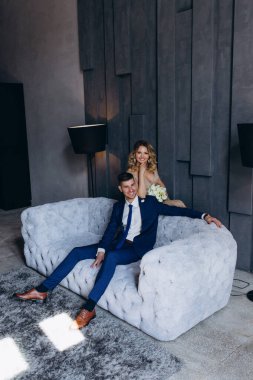 Stüdyoda gri koltukta poz veren genç ve güzel bir çift.