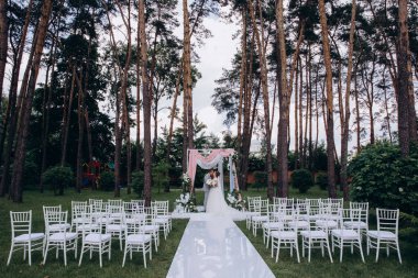 Düğün kemerinin yanında poz veren mutlu gelin ve damat parktaki düğün töreninde            
